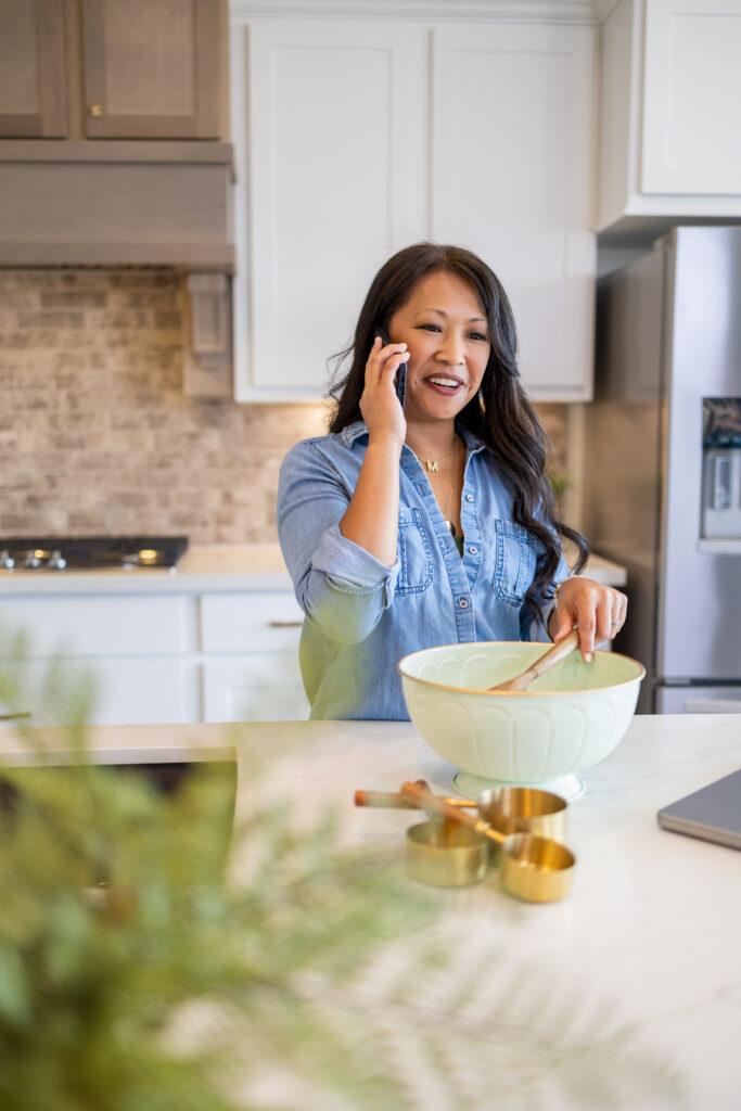 Meisie Beauvais mixing ingredients in a bowl while talking on a mobile phone